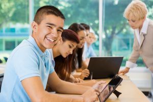 Happy teen student in private school using digital tablet